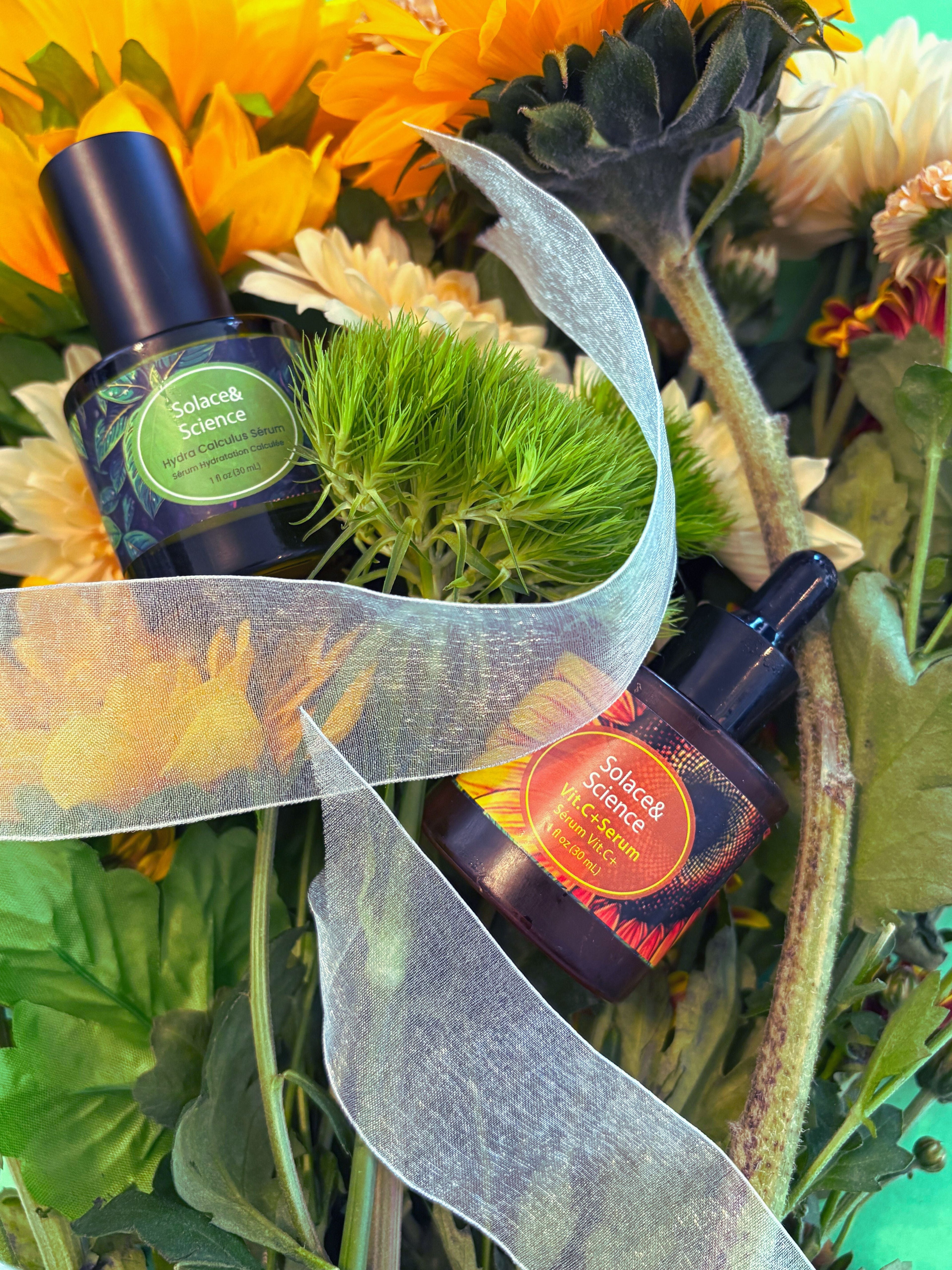 Hydra calculus serum and vitamin c+ serum amid flowers and plants and a transluscent white ribbon